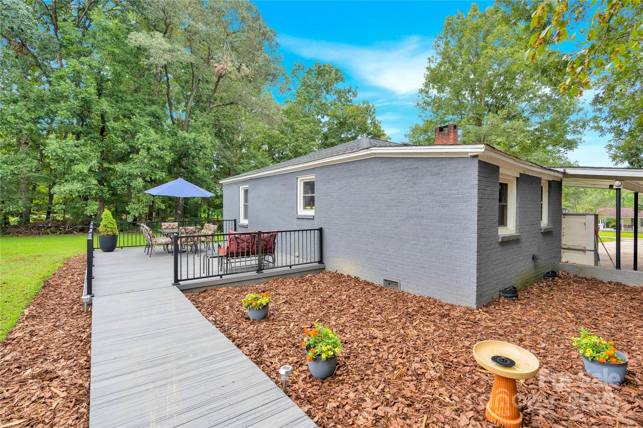 4959 King Wilkinson Road Denver, NC 28037 - Photo 22 of 41 a backyard of a house with table and chairs under an umbrella