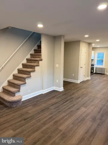 a view of an empty room with wooden floor and stairs