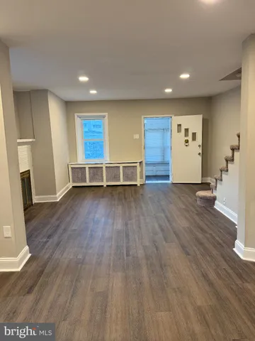 a view of an empty room with wooden floor and a fireplace