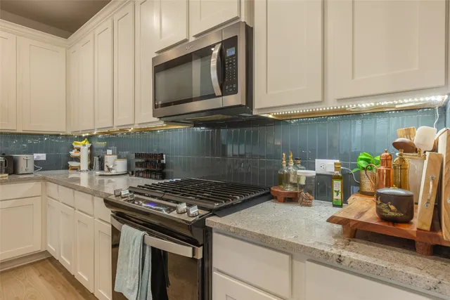 a kitchen with granite countertop white cabinets and stainless steel appliances