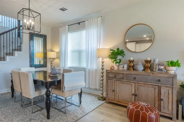 a dining room with wooden floor a chandelier a wooden table and chairs