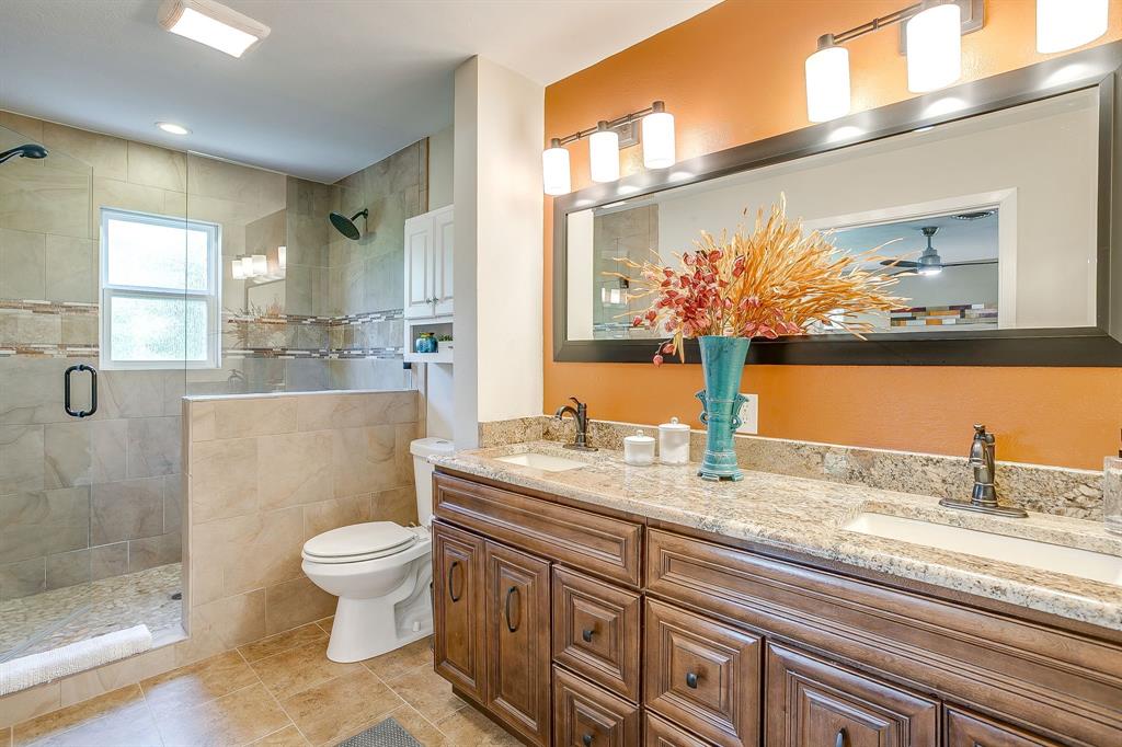 1816 Granada Road Fort Worth, TX 76116 - Photo 23 of 40 a bathroom with a granite countertop sink a toilet a mirror and shower
