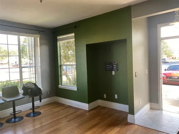 a view of an empty room with window and wooden floor