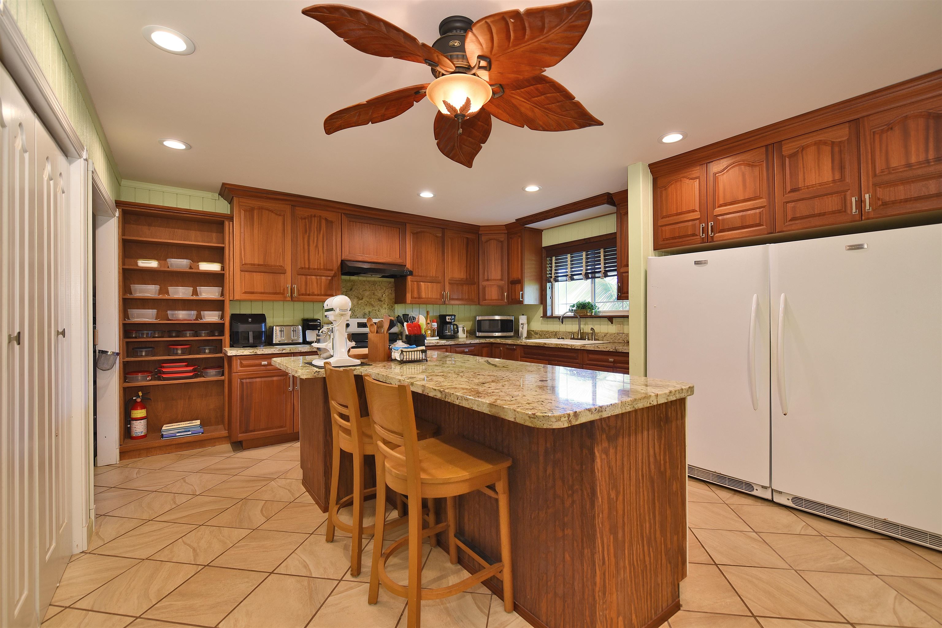 1525 Kaupakalua Road Haiku, HI 96708 - Photo 26 of 47 a kitchen with stainless steel appliances granite countertop a refrigerator a oven a sink a dining table and chairs with wooden floor