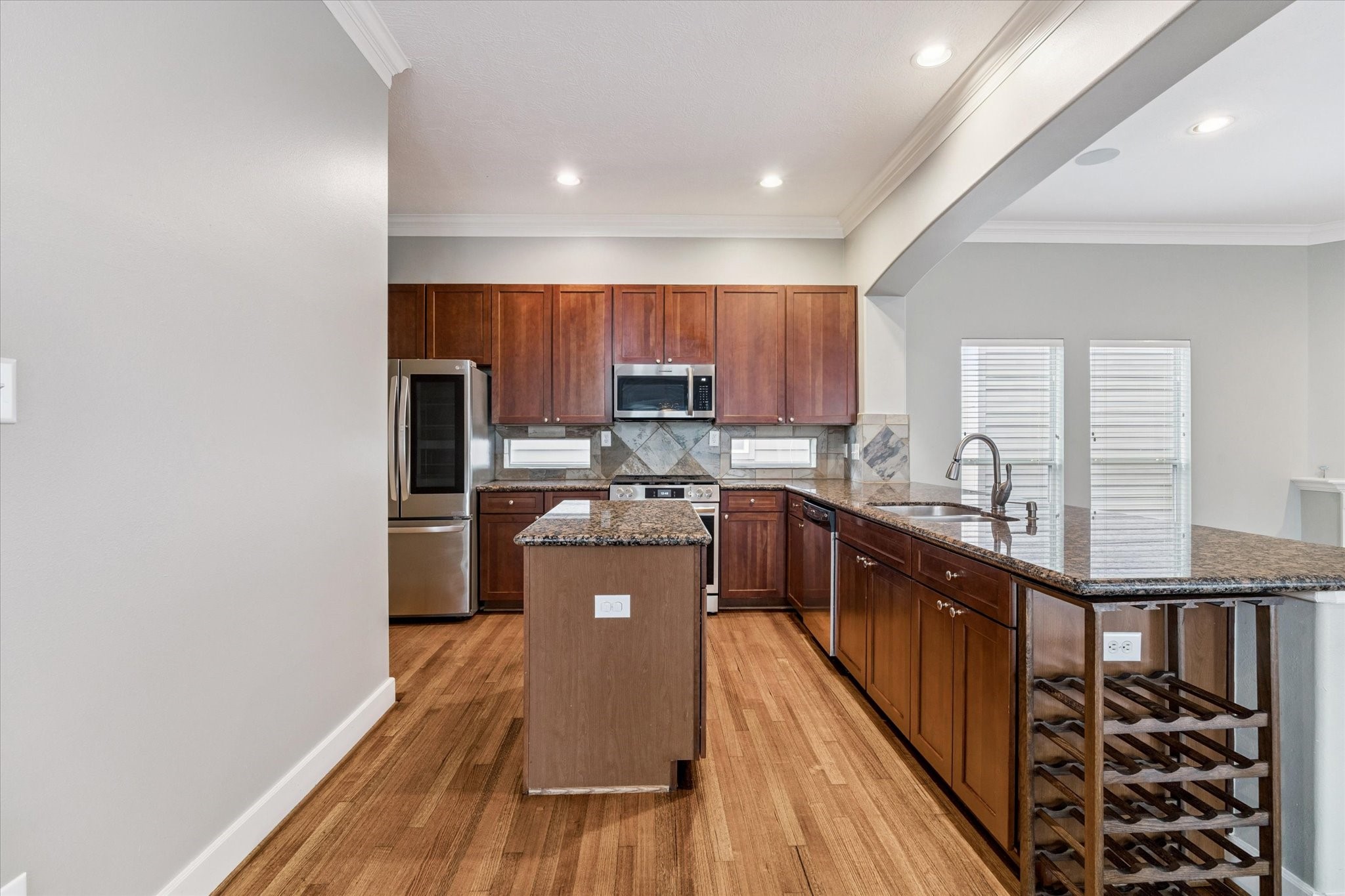 5736 Kansas Street, Unit B Houston, TX 77007 - Photo 12 of 28 a kitchen with stainless steel appliances granite countertop a refrigerator a stove top oven and a sink with wooden floor