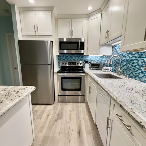 a kitchen with granite countertop a refrigerator stove and sink