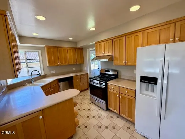 a kitchen with stainless steel appliances granite countertop a sink a stove a refrigerator a counter top space and cabinets