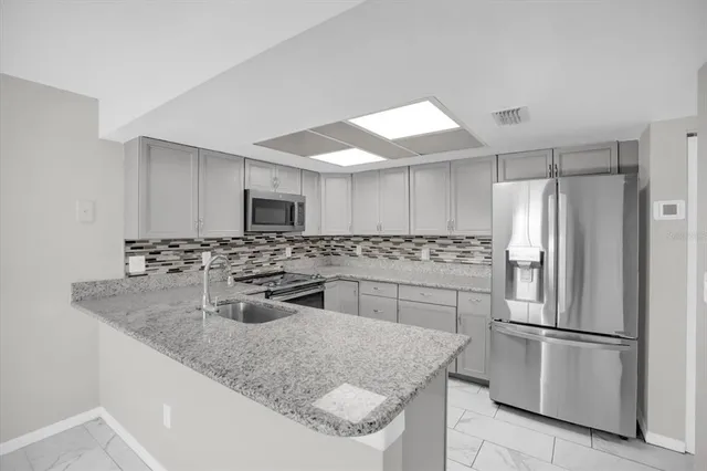 a kitchen with stainless steel appliances granite countertop a sink stove and refrigerator