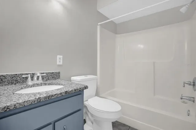 a bathroom with a granite countertop sink a toilet and bathtub