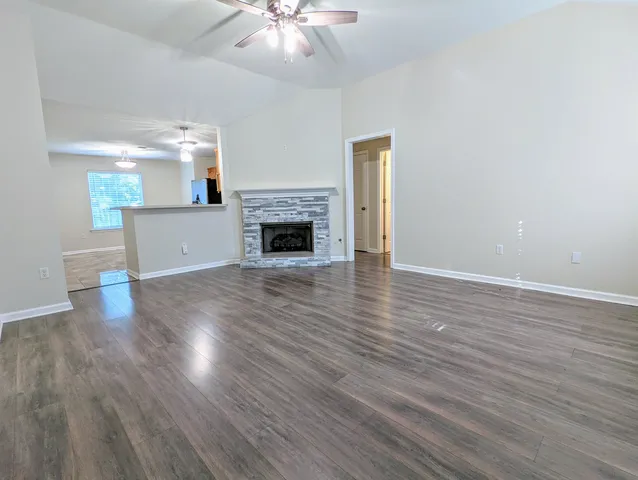 a view of an empty room with wooden floor and a fireplace