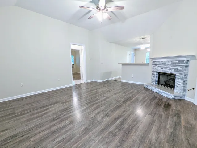 an empty room with wooden floor fireplace and windows