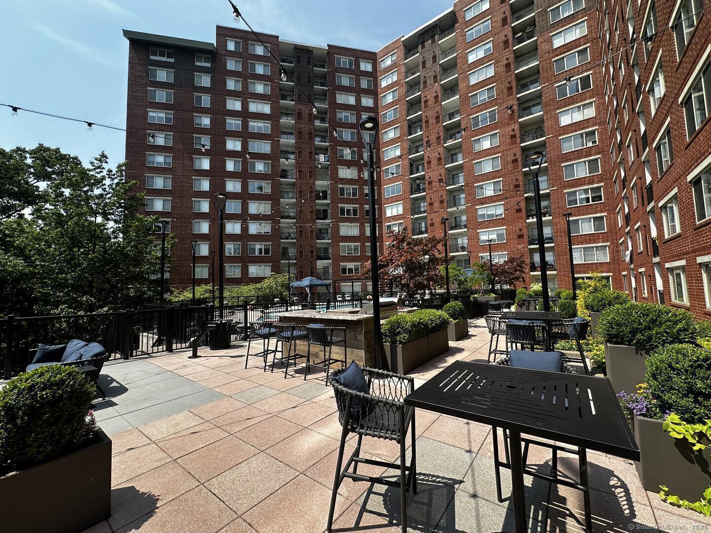 52 Forest Street, Unit 1402 Stamford, CT 06901 - Photo 12 of 23 a view of a patio with a table and chairs and potted plants