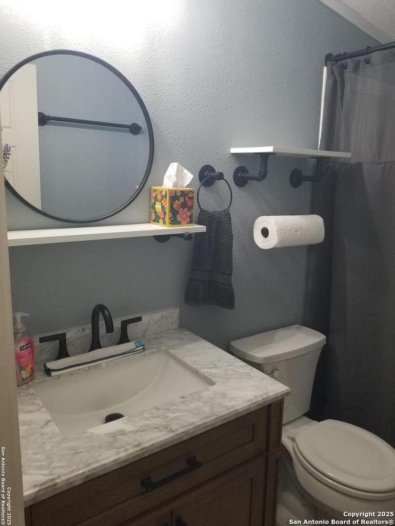 177 Laurel Ridge Drive Lakehills, TX 78063 - Photo 41 of 51 a bathroom with a toilet a sink and mirror