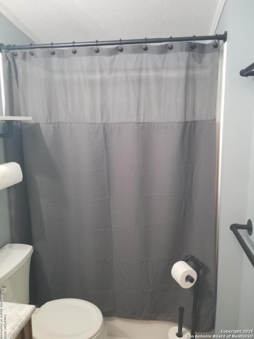 177 Laurel Ridge Drive Lakehills, TX 78063 - Photo 42 of 51 a bathroom with a toilet and a shower curtain