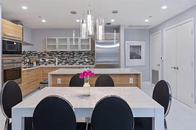 a kitchen with a table chairs a sink dishwasher refrigerator and cabinets