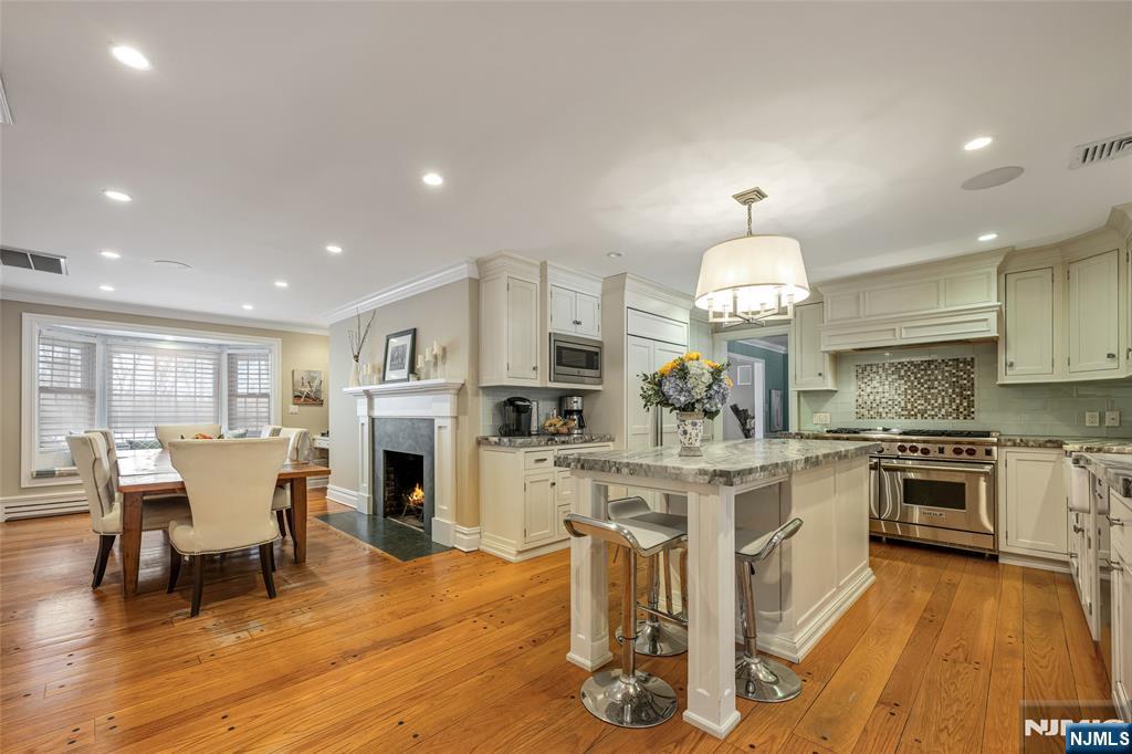 8 White Pine Road Upper Saddle River, NJ 07458 - Photo 23 of 50 a kitchen with stainless steel appliances granite countertop a stove top oven a sink dishwasher a dining table and chairs with wooden floor
