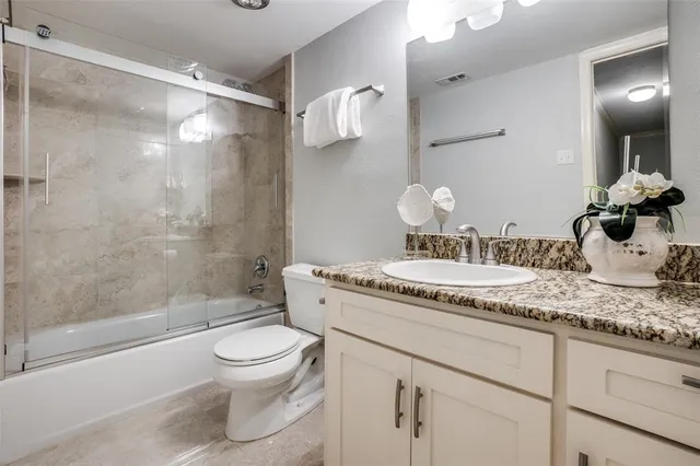 a bathroom with a granite countertop sink a toilet and shower