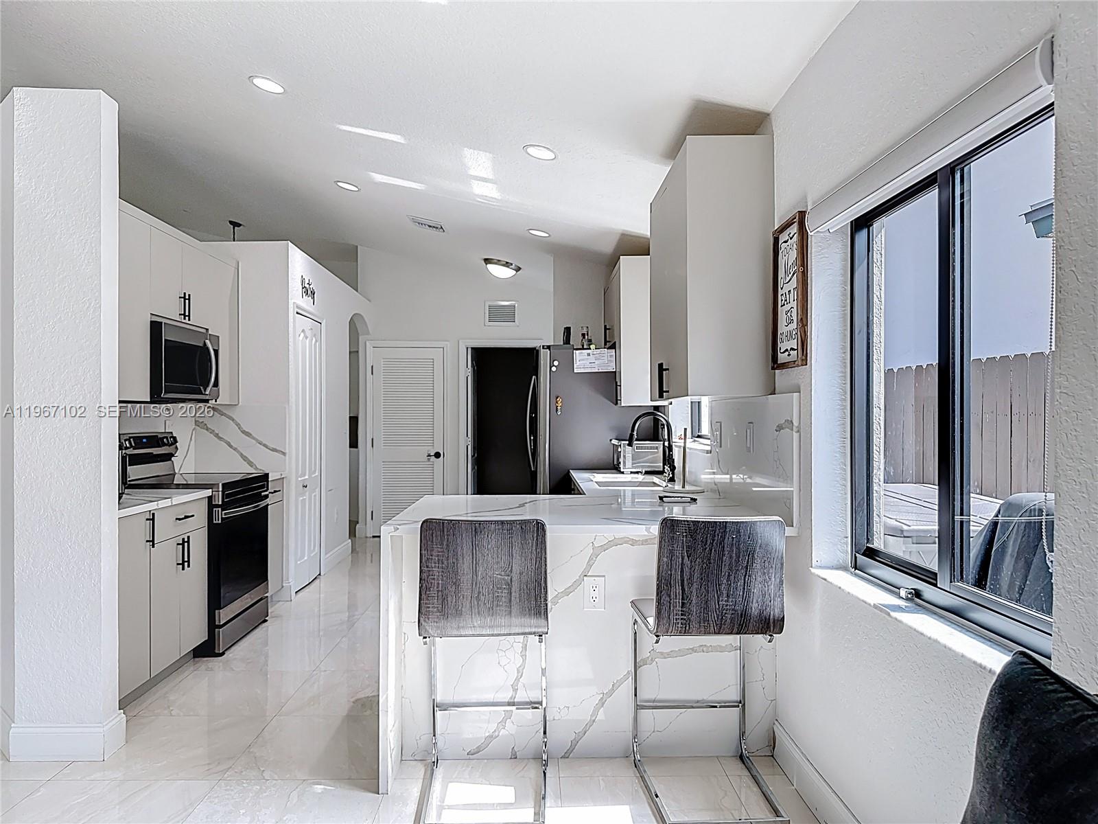 21102 Southwest 92nd Court Cutler Bay, FL 33189 - Photo 11 of 40 a kitchen with stainless steel appliances kitchen island granite countertop a stove top oven a sink dishwasher a refrigerator and white cabinets with wooden floor