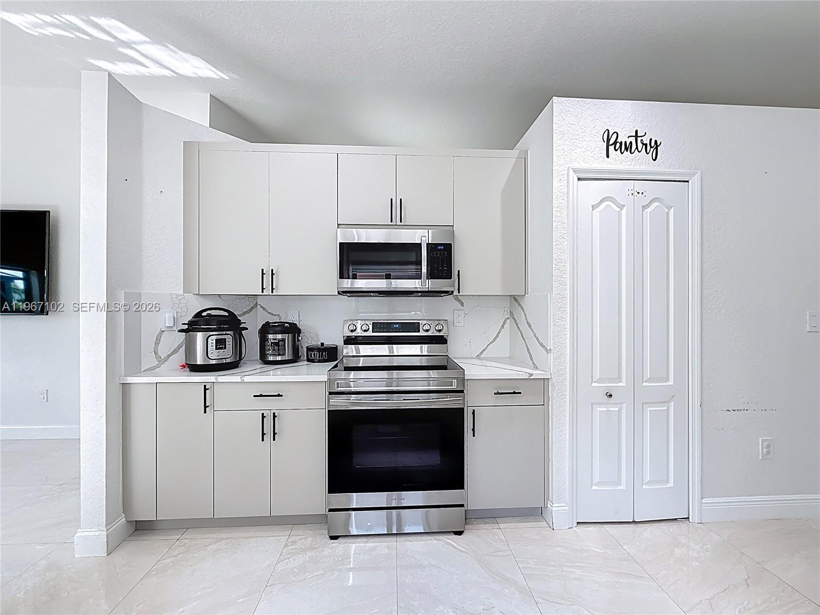 21102 Southwest 92nd Court Cutler Bay, FL 33189 - Photo 10 of 40 a kitchen with white cabinets and stainless steel appliances