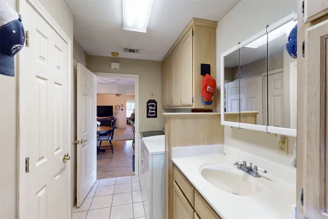 a spacious bedroom with a bed and a flat tv screen on dresser