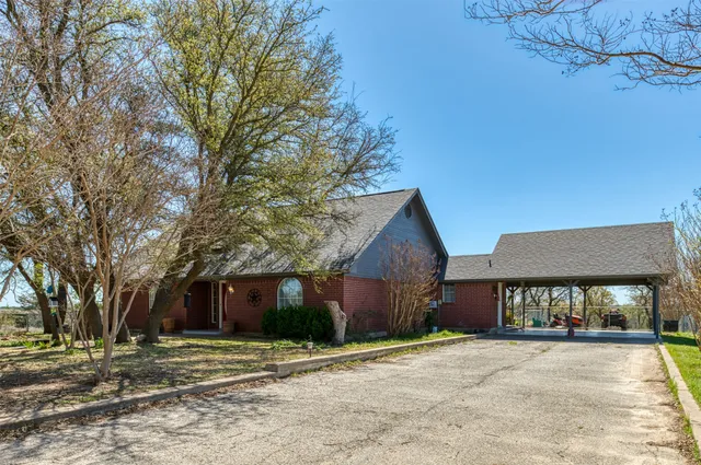 a view of a house with a yard and large tree