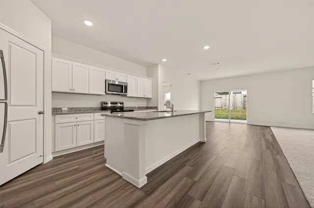 a kitchen with granite countertop kitchen island stainless steel appliances a sink stove top oven and cabinets