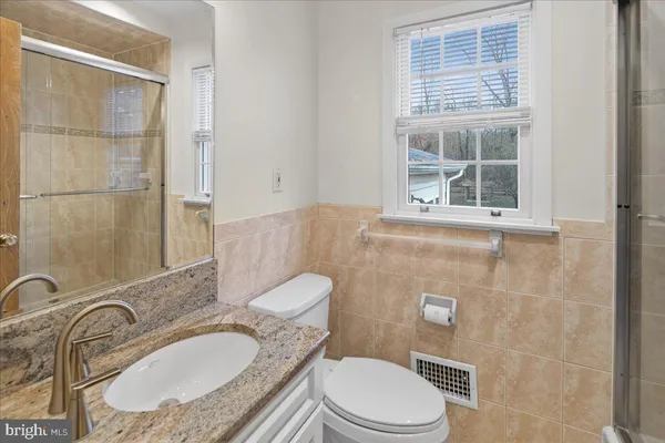 a bathroom with a granite countertop toilet a sink and mirror