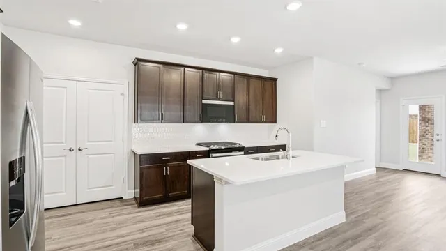 a kitchen that has a sink a stove and wooden floor
