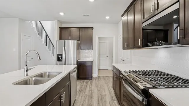 a kitchen with stainless steel appliances kitchen island a sink stove and refrigerator
