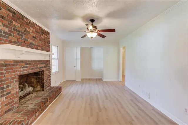 a view of a livingroom with a fireplace a ceiling fan and wooden floor