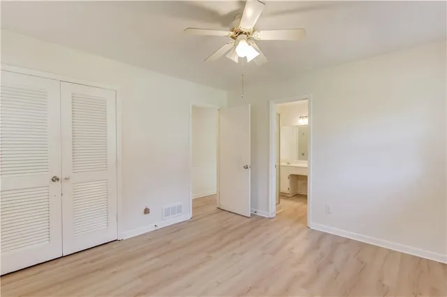 an empty room with wooden floor and ceiling fan