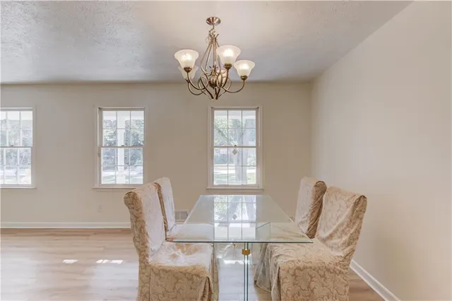 a view of a dining room with furniture a chandelier and a window