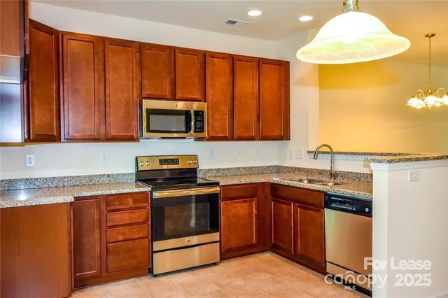 a kitchen with stainless steel appliances granite countertop wooden cabinets a stove top oven a sink and dishwasher