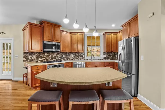 a kitchen with stainless steel appliances a table chairs microwave and sink