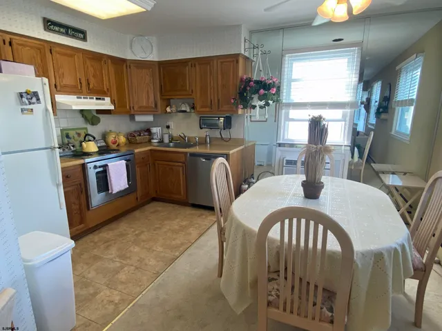 a kitchen with stainless steel appliances granite countertop a refrigerator a stove a sink dishwasher and white cabinets with wooden floor