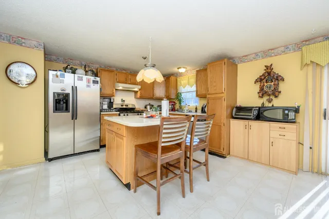 a kitchen with stainless steel appliances kitchen island granite countertop a refrigerator and a stove top oven