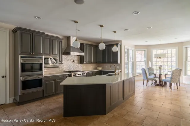 a kitchen with stainless steel appliances granite countertop a stove top oven a refrigerator a sink and a dining table