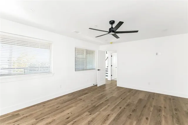 an empty room with wooden floor cabinet and windows