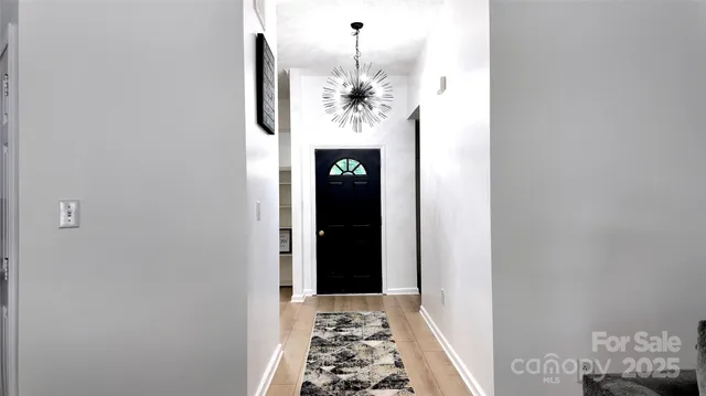 a view of a hallway with wooden floor and a chandelier