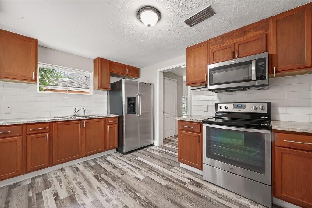1511 Scharpe Street, Unit 2 Houston, TX 77023 - Photo 5 of 27 a kitchen with stainless steel appliances granite countertop a stove microwave and refrigerator