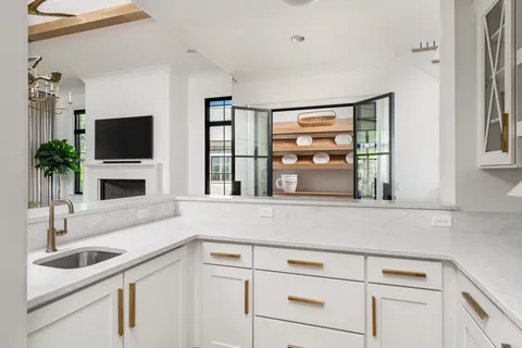 a kitchen with a sink dishwasher a stove top oven a dining table and chairs with wooden floor