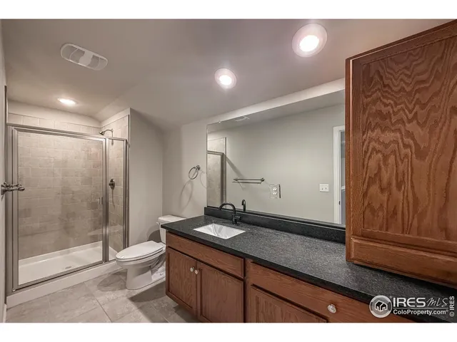 a bathroom with a granite countertop sink a toilet a glass door shower and a mirror
