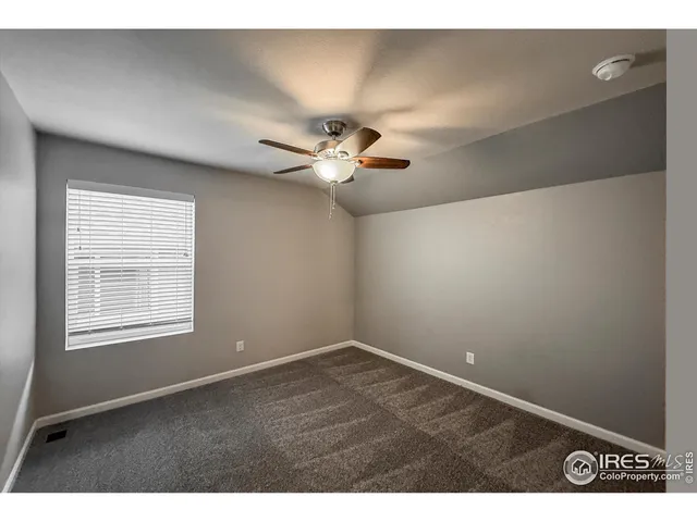 a view of an empty room with a ceiling fan and a window