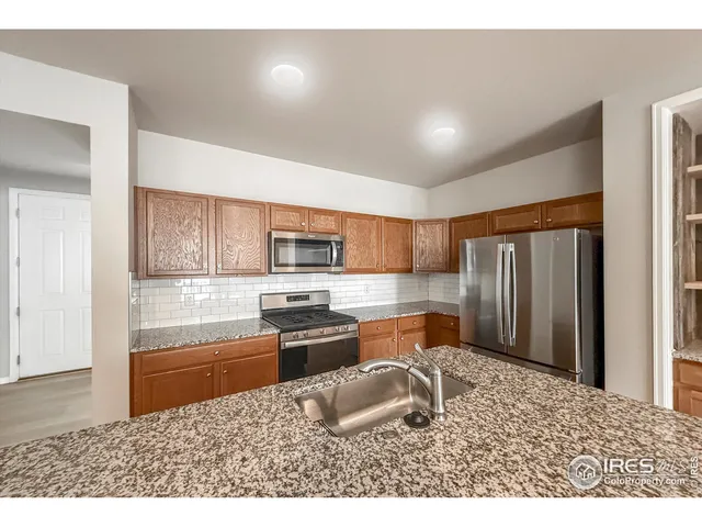 a kitchen with stainless steel appliances granite countertop a sink refrigerator stove and microwave