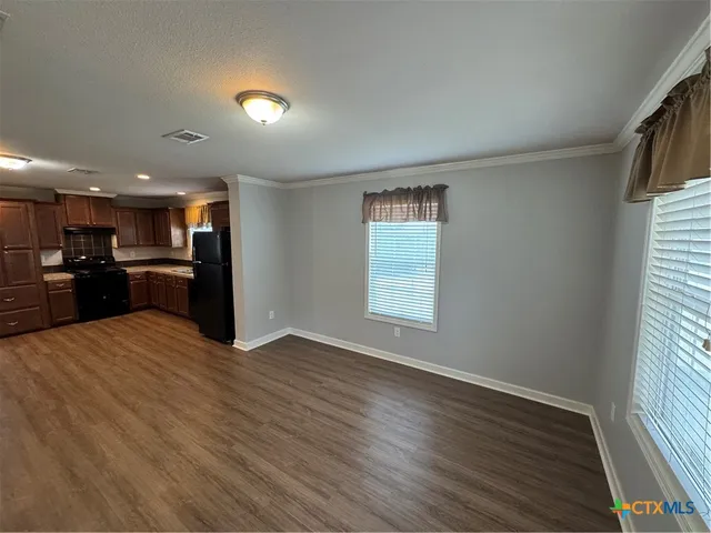 a view of a electric appliances in a hall with wooden floor and a window
