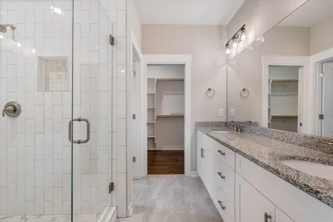 a spacious bathroom with a granite countertop sink a mirror and shower