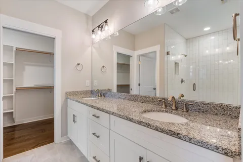 a bathroom with a granite countertop double vanity sink and a mirror