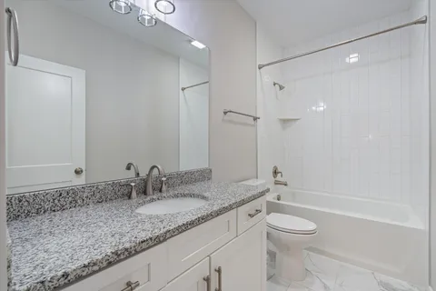a bathroom with a granite countertop sink a toilet and shower