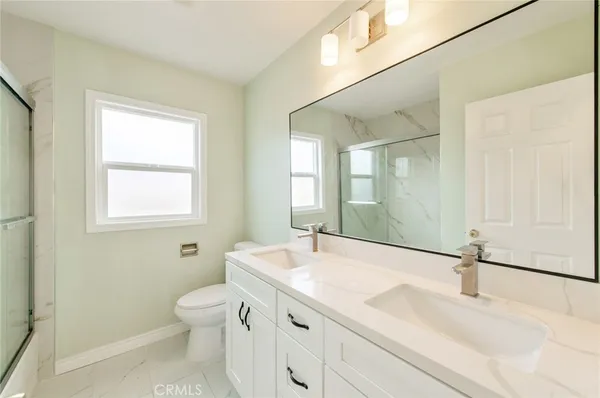 a bathroom with a granite countertop sink a toilet and a mirror