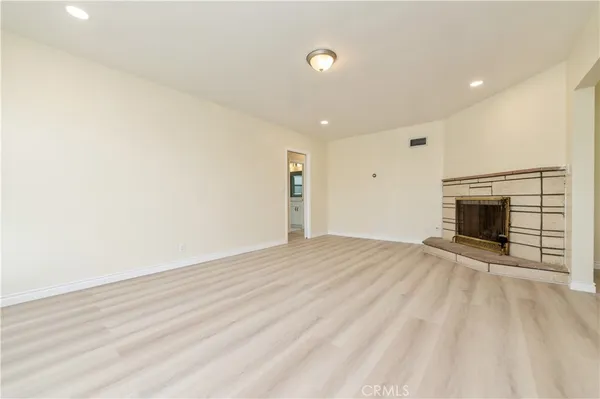 a view of empty room with wooden floor and fireplace